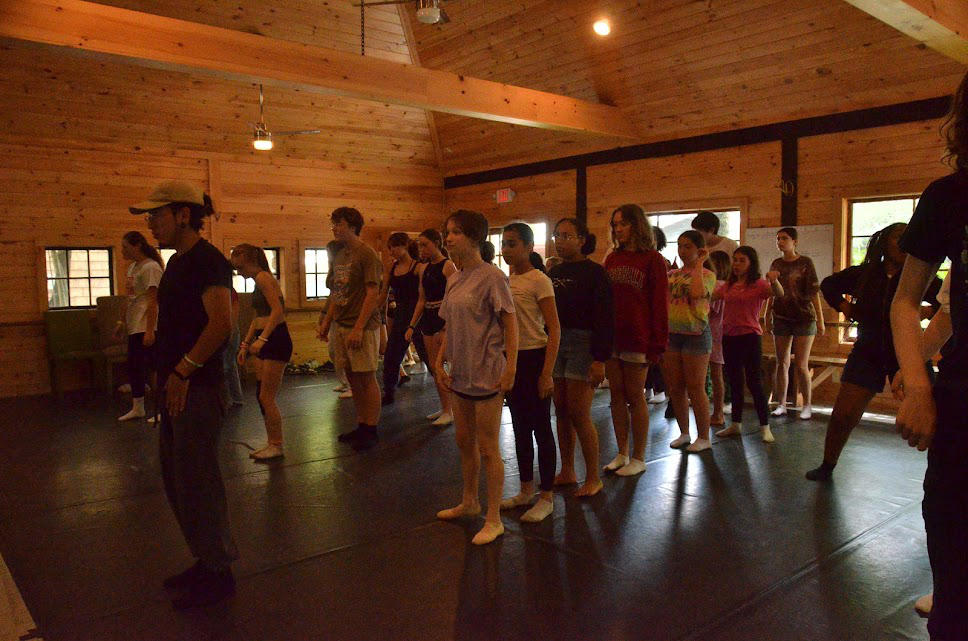 Picture21 – Long Lake Camp For The Arts Group of campers standing behind a professional dance instructor preparing for rehearsal in a studio
