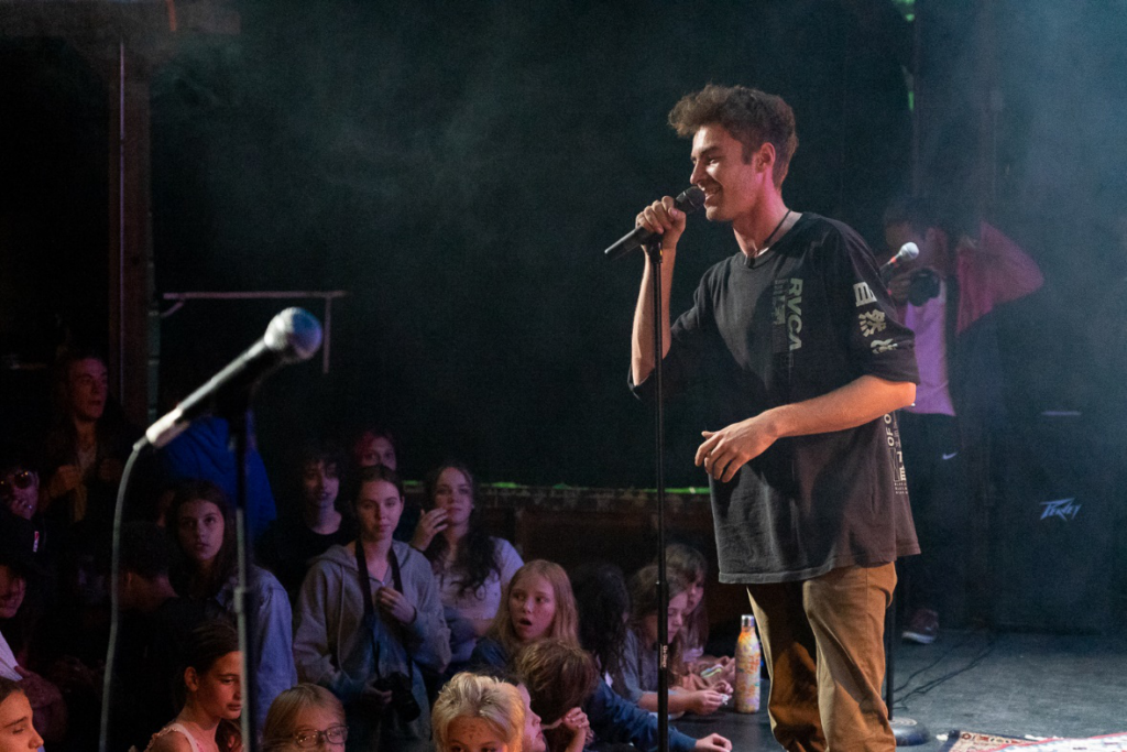 Picture23 – Long Lake Camp For The Arts Camper performing on stage in front of an audience at rock camp