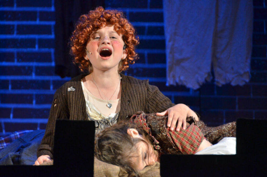 Picture26 – Long Lake Camp For The Arts Teen camper performing a role in the musical Annie on stage with costumes