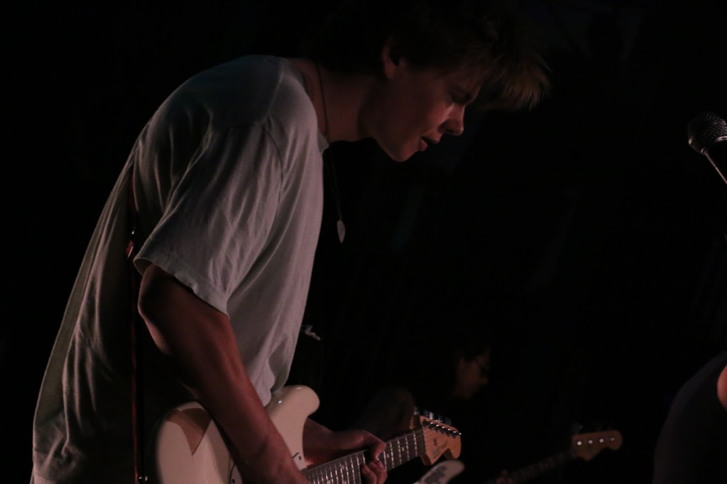 A teen camper playing an acoustic guitar at rock camp.