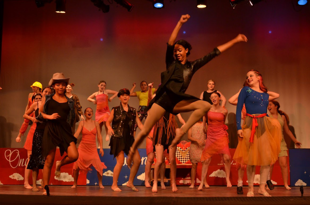 Campers dancing confidently on stage during a summer dance camp performance.