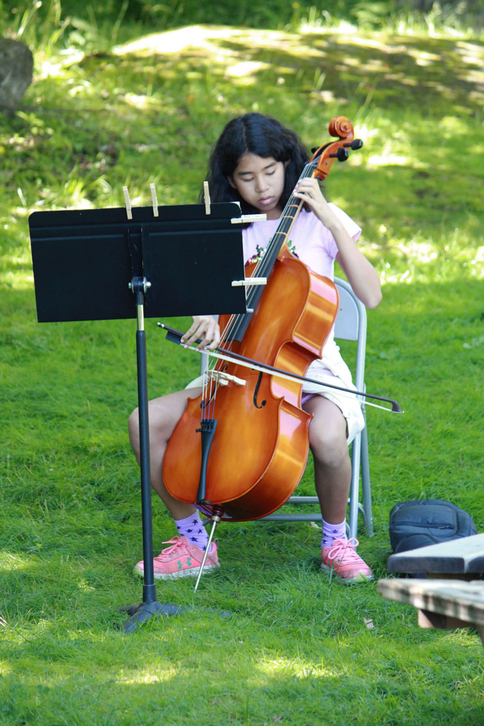 Teen girl playing violin during a music session at camp
