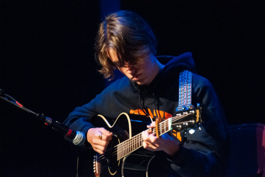 Teen camper playing guitar during a summer arts camp activity